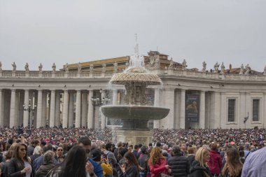 Vatican City / Rome / Italy - April 21, 2019: Crowd of people celebrating Easter Mass in St. Peter's Square. Vatican fountain in the middle.