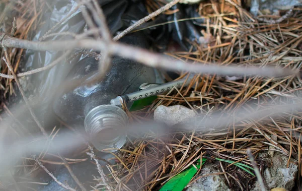 用过针头注射器和其他垃圾在森林中的地面上 吸毒者留下的注射器 — 图库照片