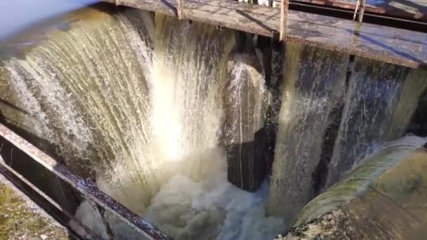 Slow motion tittar ner på dammluckan. Översvämmat brunt vatten forsar igenom. — Stockvideo