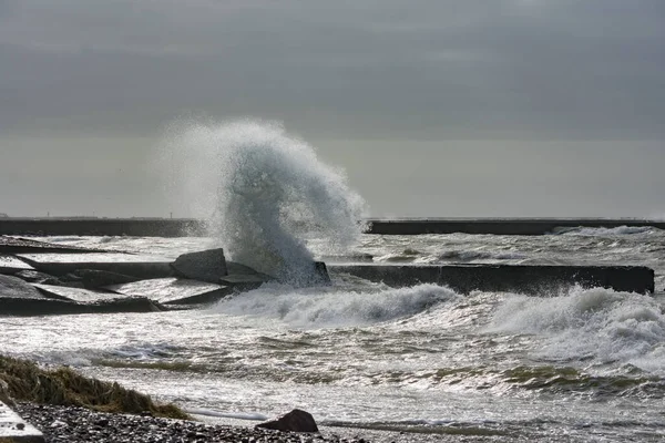 Big splash of water. Waves hitting concrete sea wall pier