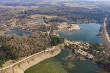 Terk edilmiş eski bir kumsalın havadan görünüşü, çakıl ocağı yeşil suyla dolu.