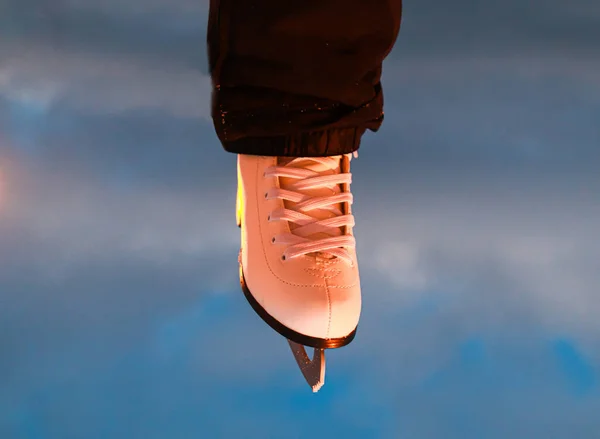 Gökyüzü arka planında beyaz buz patenlerini takan bacak