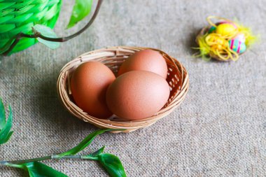 Paskalya yumurtaları ve kahverengi kumaş üzerinde küçük dekoratif yumurtalar.