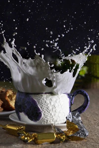 Siyah zemin üzerinde süt ve şeker lekeleri olan mavi seramik bardak.