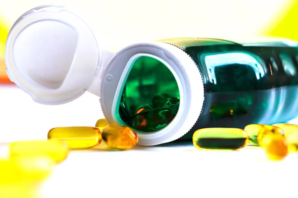 Yeşil şişedeki sarı hap, beyaz arka plan, ilaç, vitamin. Şişenin kenarındaki haplara odaklan.