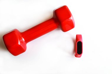 Red dumb bells with digital sport tracker isolated on white background. Copy space