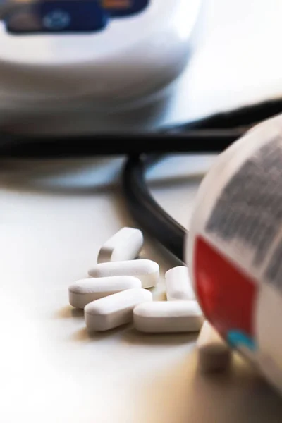 Beyaz arka planda tonometreyle beyaz haplar. Tıp teması, sağlık hizmeti