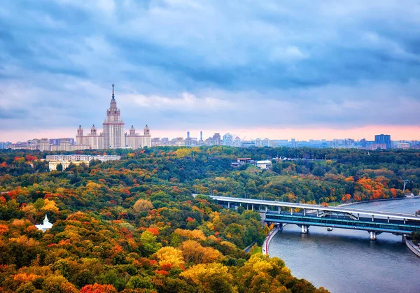 Дощові хмари заходу сонця над річкою, парком, мостом, кораблями і великим с — стокове фото