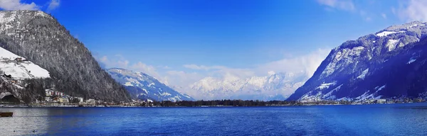 Panorama of winter slope of sunny morning Alps with village hous — Stock Photo, Image