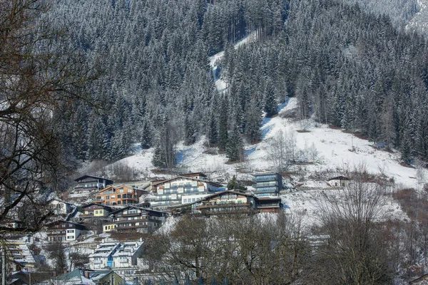 Winter slope of Alps with sunny village houses, snow and forest — стокове фото