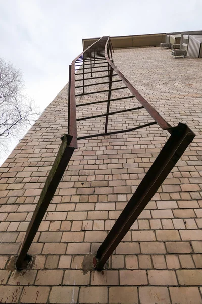 Rusty metallic fire stairs on brick wall of residential house in