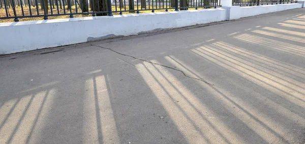Long morning shadows on cracked asphalt road — 图库照片