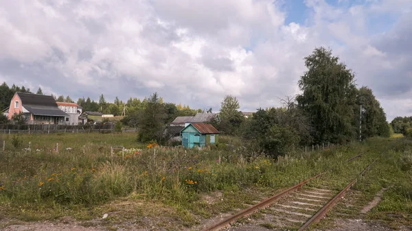 Camino de ferrocarril oxidado abandonado en el campo bajo un cielo dramático —  Fotos de Stock
