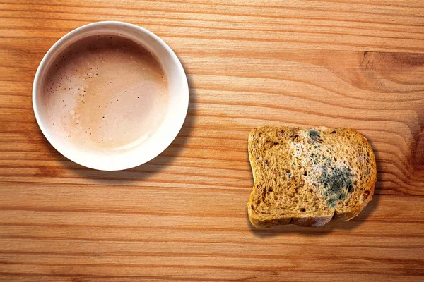 Hot coffee mug and mold bread on striped wooden desk