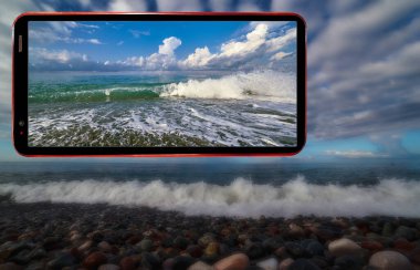 Karadeniz 'in güneşli dalgalarını akşam kumsalının bulanık arka planında ıslak taşlarla gösteren cep telefonu kolajı