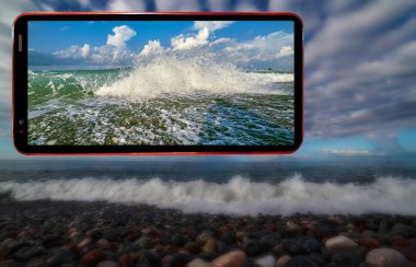 Karadeniz 'in Soçi bölgesinde ıslak taşlarla kaplı dalgalı deniz plajının karanlık gizemli arkaplanındaki cep telefonu ekranı kolajı