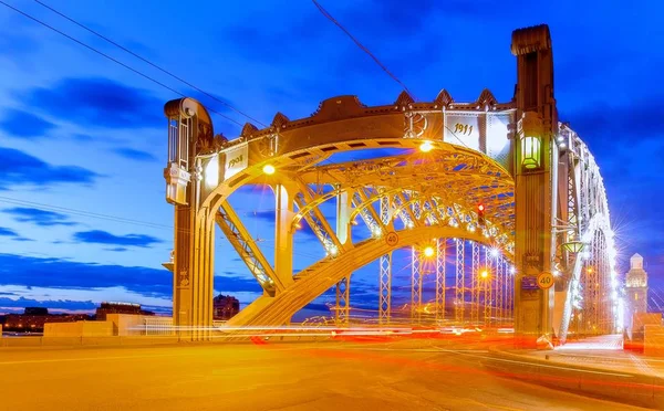 Stock image Vibrant view of famous city river steel crossover entitled as The Peter the Great bridge in Saint - Petersburg and light tracers on sunset