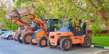 Moscow, Russia - 9 August 2017: Road industrial orange machines on asphalt near residential building under green trees 