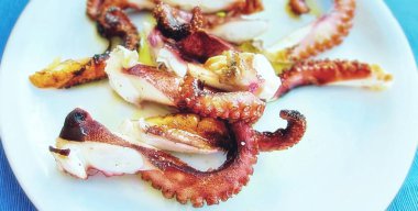 Kıbrıs 'ta beyaz tabak üzerinde kesilmiş yağlı ahtapot parçalarının bulanık görüntüsü