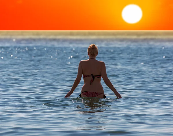 Silhouette of happy lady going to swim  during sunset