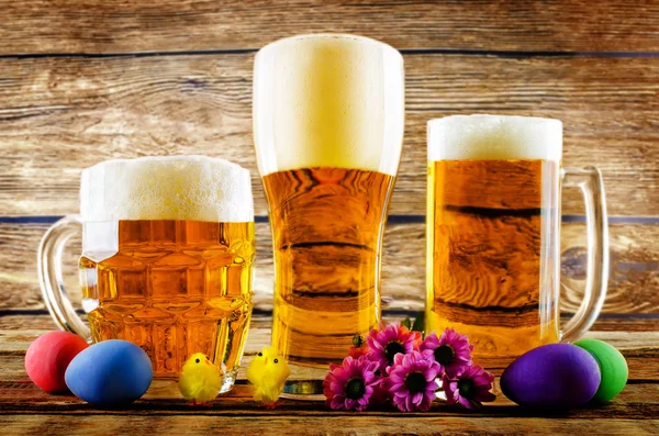 Glass of cold light beer with Easter decorations on a wood backg