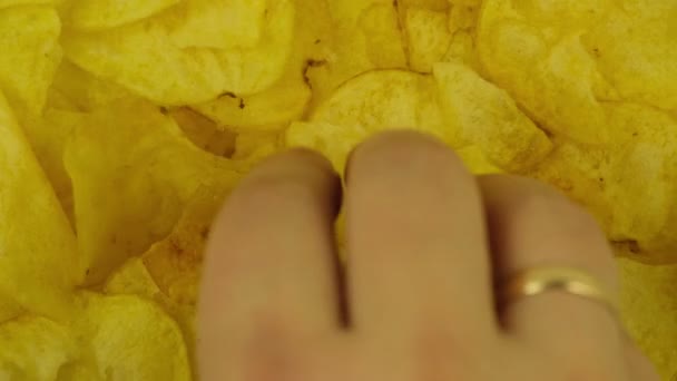 Az ember elveszi a sárga burgonyaszirmot a forgó tányérról. — Stock videók