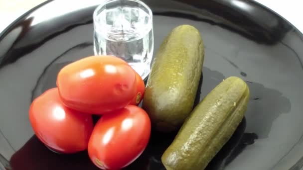 Sklenici vodky, okurky a nakládaná rajčata na talíři — Stock video
