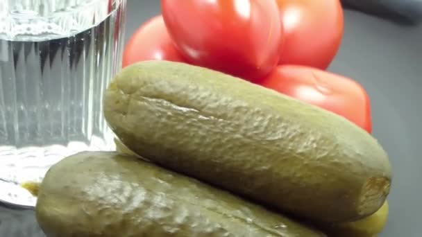 A big glass of vodka, cucumbers and tomatoes in a plate — Stock videók