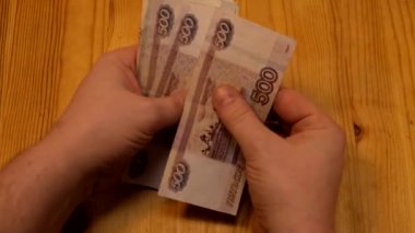 Bir adam sarı arka planda elleri ile dolarları sayar.