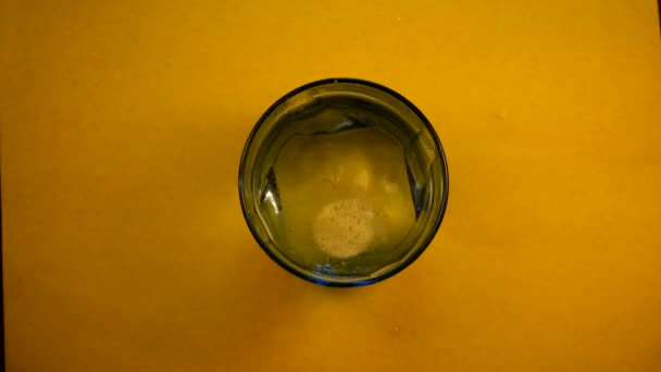 The effervescent tablet dissolves in a glass of water. Close up. The view from the top — Stock Video
