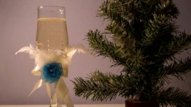 Şampanya köpükleri suni bir Noel ağacının yanında özel tasarım bir bardakta.
