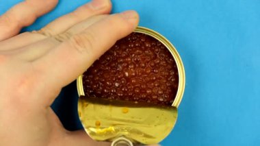 Erkekler kırmızı havyar kavanozunun kapağını açar. Üst Manzara. Kavanozları kırmızı havyarla açıyorum. Yukarıdan manzara. Yakın plan. Makro.