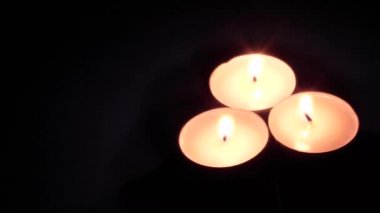 Üç yanan mum - tabletler siyah arkaplanda dönüyor. metin alanı.