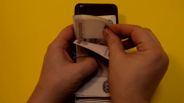 Hombre cuenta rublos en bolso sobre fondo naranja . — Vídeos de Stock