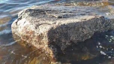 Dalgalar büyük granit taşı yuvarlar. Finlandiya 'nın Baltık Denizi körfezi. Bahar.