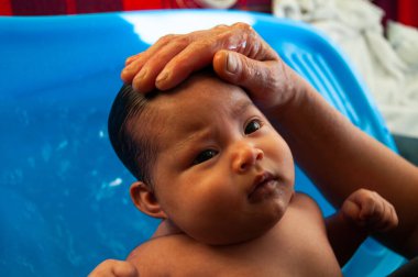 Küçük bebek gün ışığında banyo yapıyor.