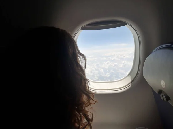 Lookking out of the plane window at a desert landscape girl long hair silhouette