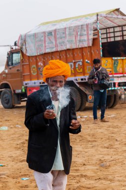 Puşkar, Rajasthan / Hindistan - Kasım 2019: Fuar alanında sigara içen yaşlı adam