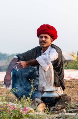 Pushkar, Rajasthan / India - November 2019 : Portrait of camel traders participating with their camels in pushkar camel fair in traditional white rajasthani dress and colorful pagadi (Turban) on their head 