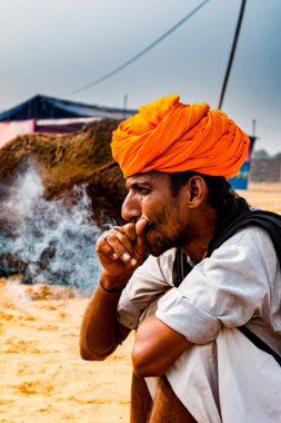 Pushkar, Rajasthan / India - November 2019 : Rajasthani camel owner /traders smoking in the camel fair ground