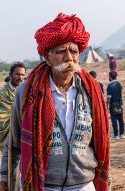 Pushkar, Rajasthan / India - November 2019 : Portrait of rajasthani camel owner/trader in colorful turban and white dress with big mustache participating in camel trading fair