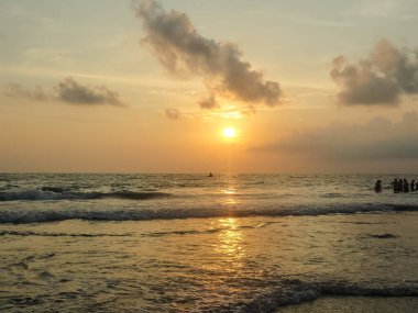 Goa sahillerinde, karamsar gökyüzü ve turistlerle birlikte Arap denizlerinde gün batımı manzarası