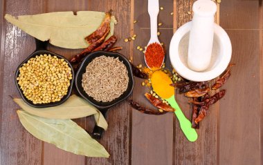 Hint baharatları ve otları kaşık ve kase üzerinde ahşap arka planda.