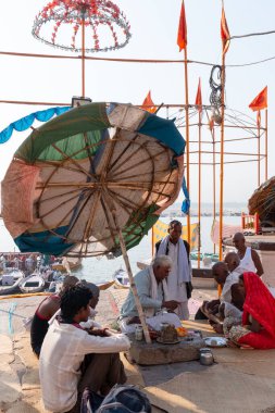 Varanasi, Uttar Pradesh / Hindistan - Nisan 2019: Varanasi 'deki Dasaswamedh Ghat' ta bir rahibin yardımıyla Ganga nehrine tapan hacılar