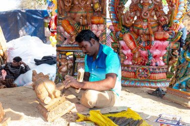 FARIDABAD, HARYANA / INDIA - Şubat 2020: Hintli erkek sanatçı Surajkund Sanat Fuarında tahta ile Hint tanrısını putlaştırıyor