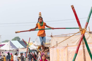 PUSHKAR, RAJASTHAN / INDIA - NOVEMBER 2019: Pushkar Fuarı 'nda sıkışık halatla akrobasi yapan ve bambuyla dengeyi sağlayan genç kız