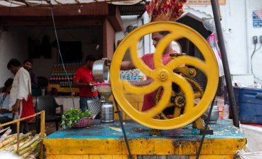 Sokak satıcısı Hindistan, Pushkar 'da şeker kamışı suyu yapıyor.