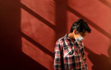 Virüslerden ve mikroplardan korunmak için yüzüne tıbbi maske takan genç bir çocuk. Renkli arkaplan ile Kavramı Temizle.