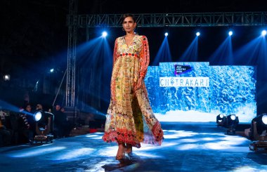 Aralık 2020 'de Yeni Delhi, Hindistan' daki moda fuarında bir model modacı etnik bahar koleksiyonu giyerek podyumda yürüyor.