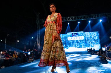 Aralık 2020 'de Yeni Delhi, Hindistan' daki moda fuarında bir model modacı etnik bahar koleksiyonu giyerek podyumda yürüyor.